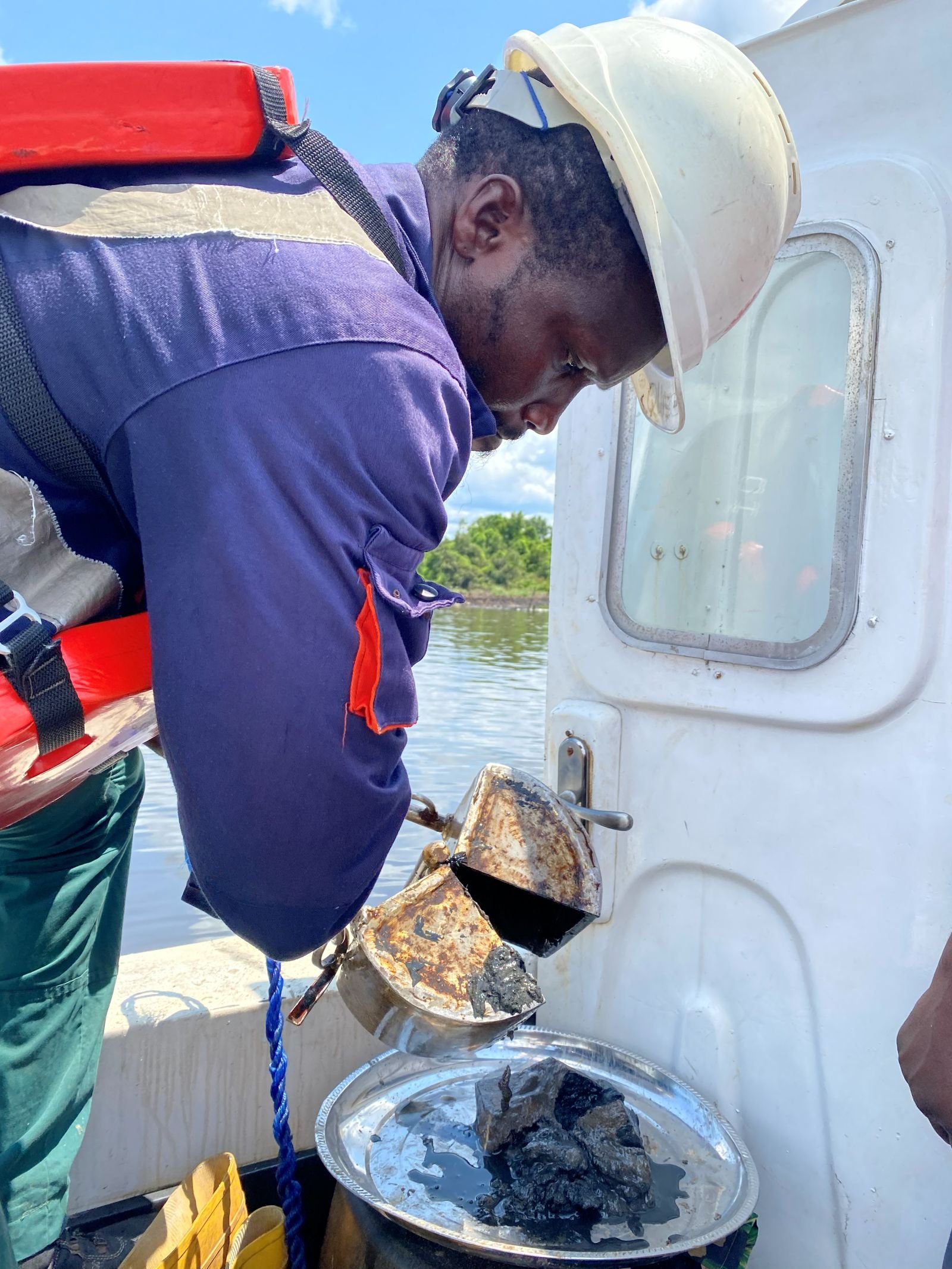 Engineer inspecting a recovered sediment grab sample offshore